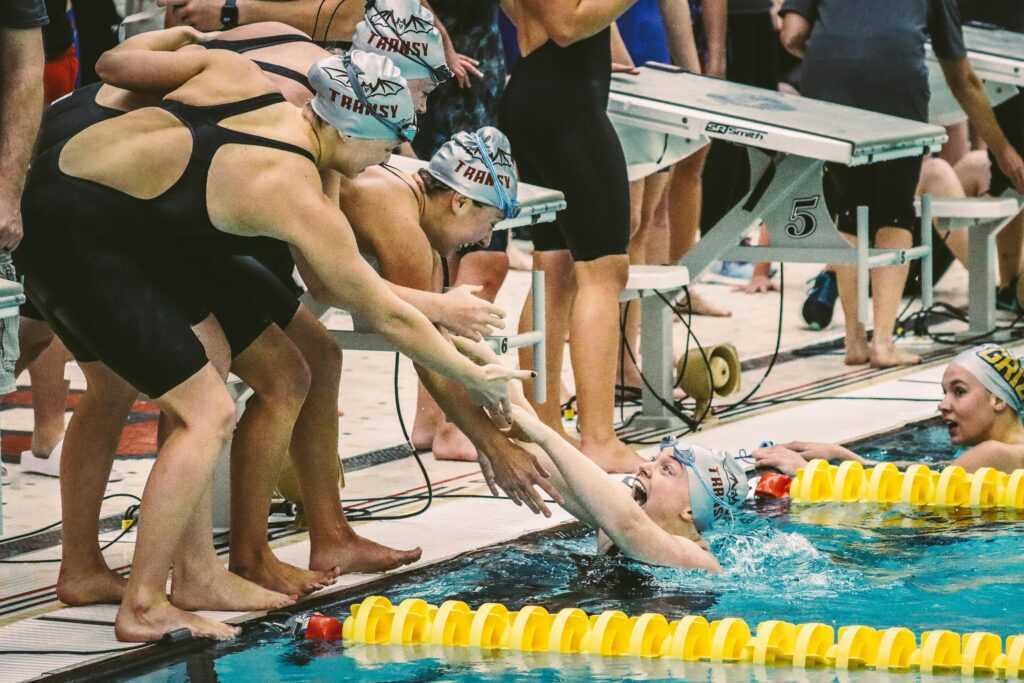 Euphoric swimmers celebrate victory at a swimming meet, showing team spirit and joy.